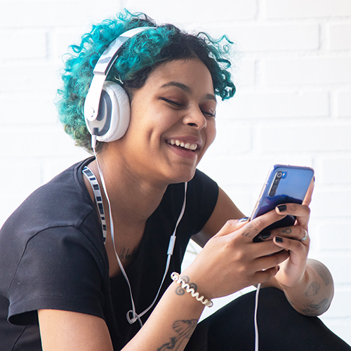 Person with teal hair and headphones enjoying their phone