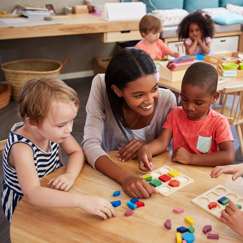 Small children sitting at a table doing colorful puzzles