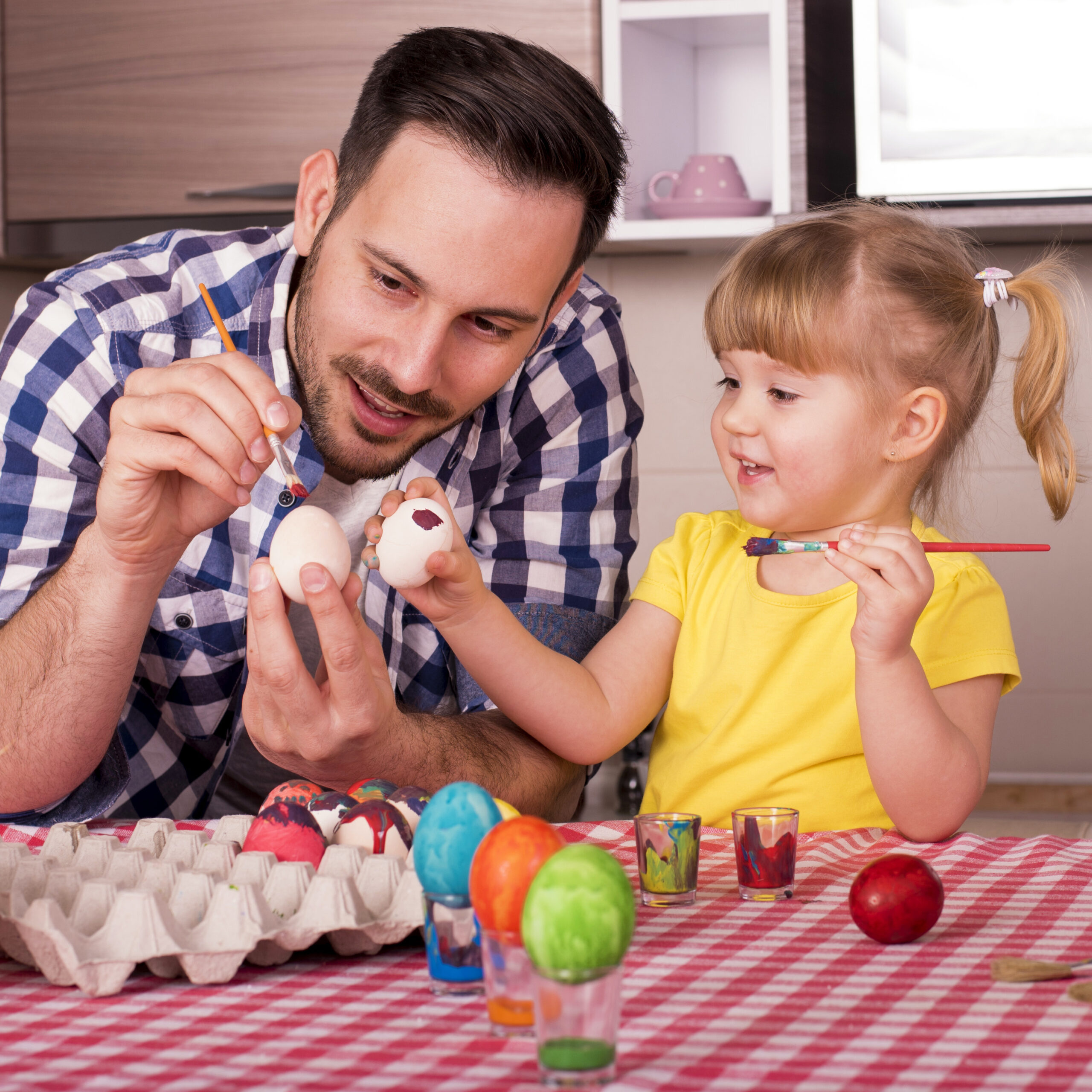 Father and his little child painting easter eggs