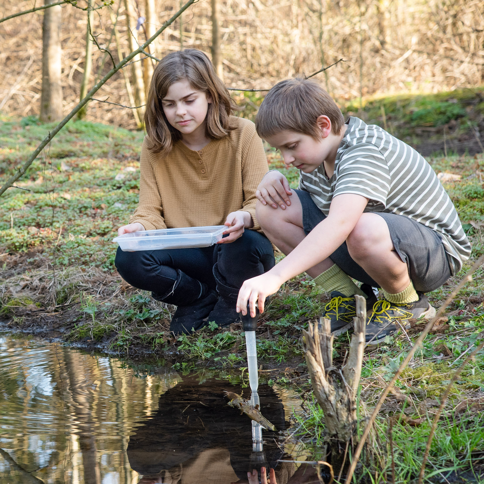 Kids testing pond water in a science experiment