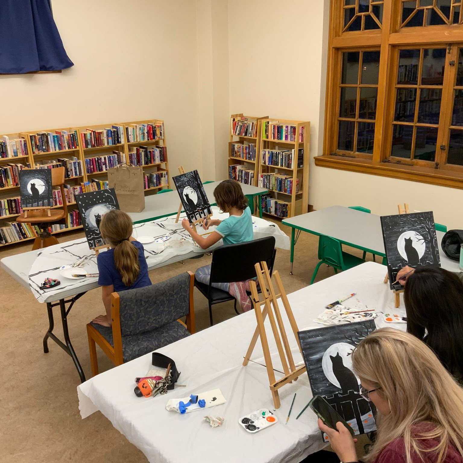 People painting a Halloween scene on canvas