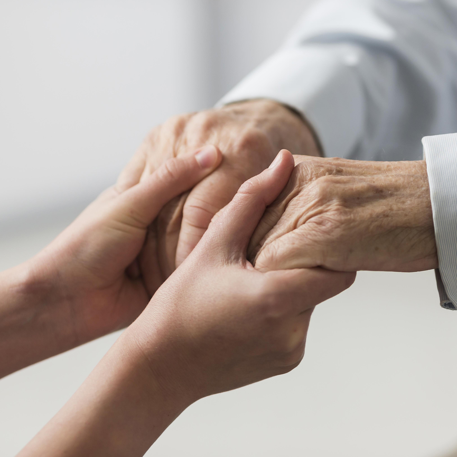 Younger set of hands holding an elderly set of hands