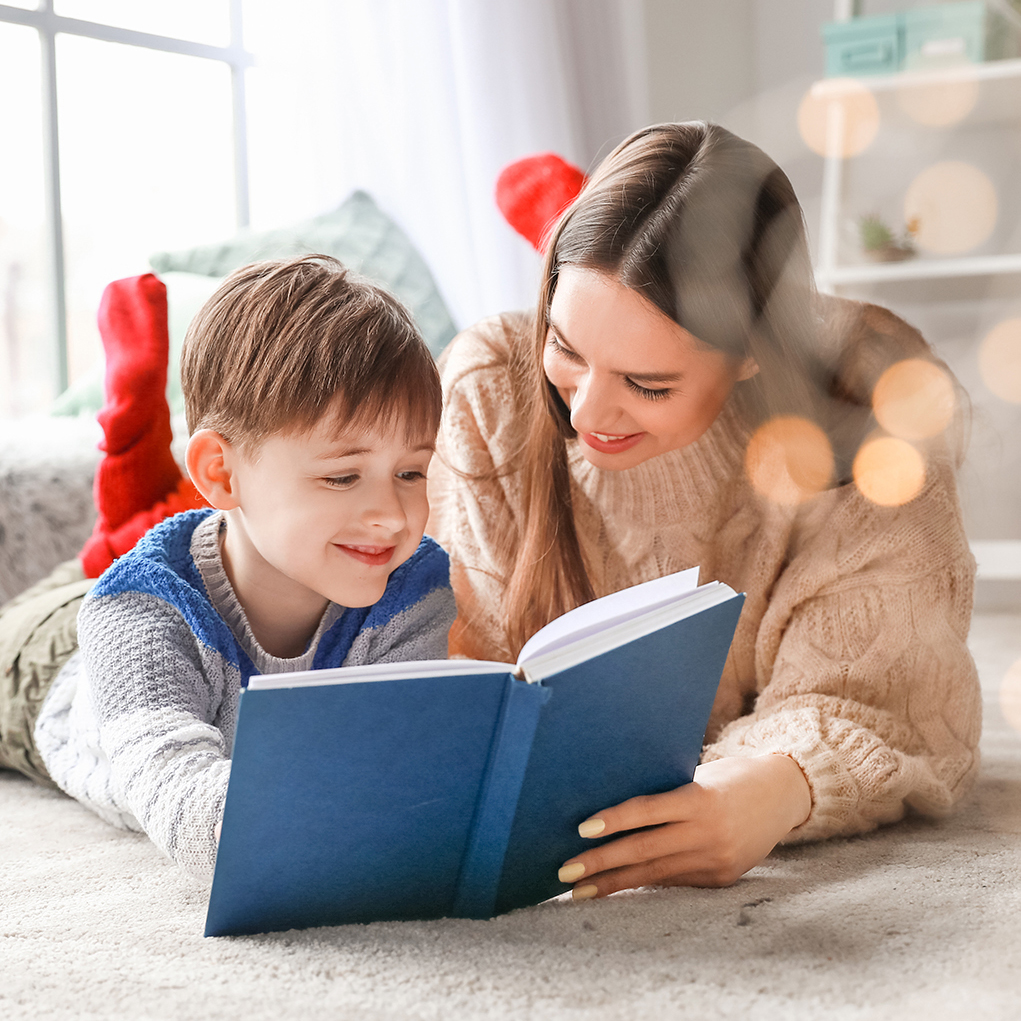 Little boy with mother reading book at home