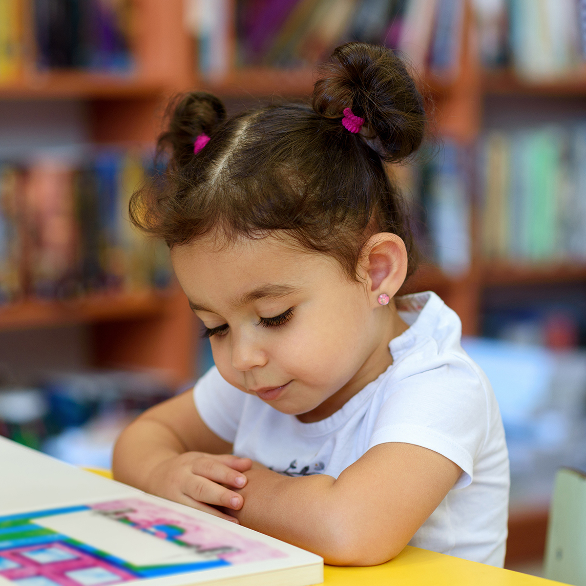 Toddler reading a book in a library