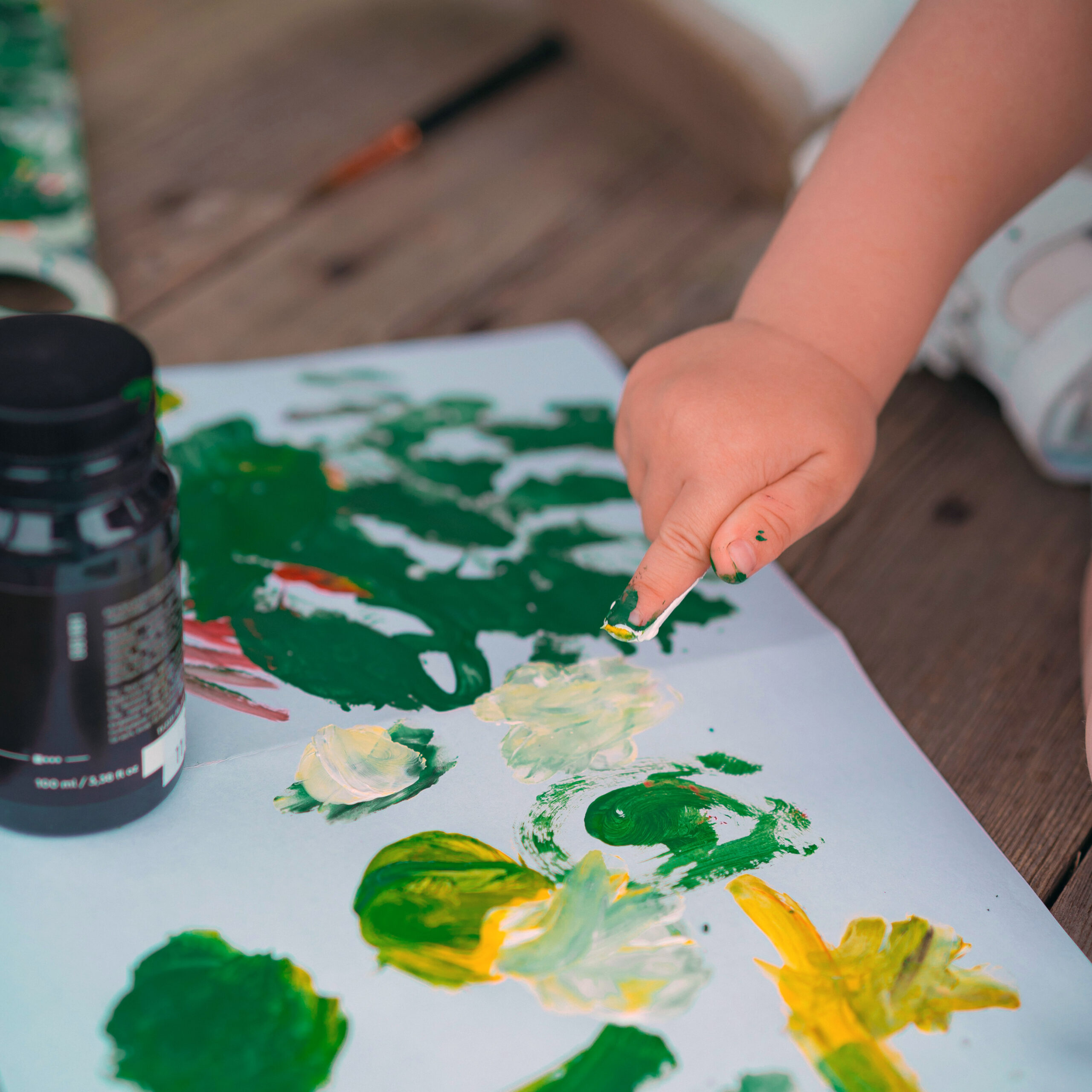 Baby using its hand to paint on a paper