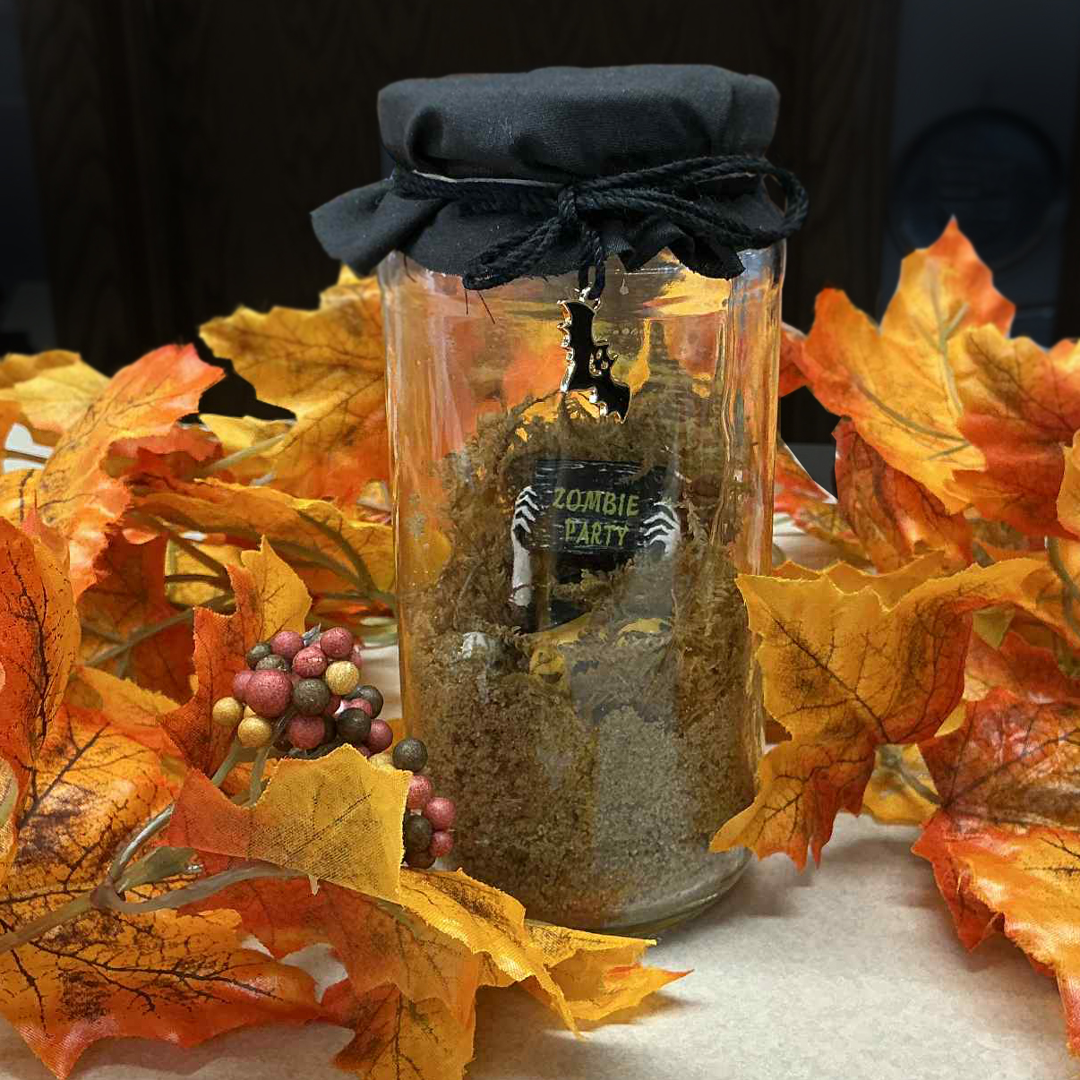 Halloween themed jar with sand and orange leaves around it
