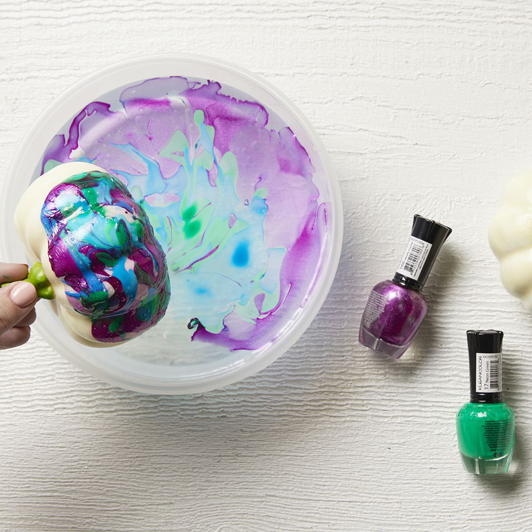 Mini pumpkin dipped in nail polish to marbleize it.