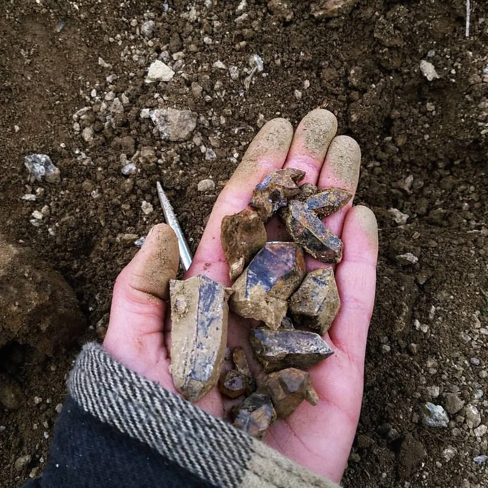 Adult hand holding dirt covered crystals