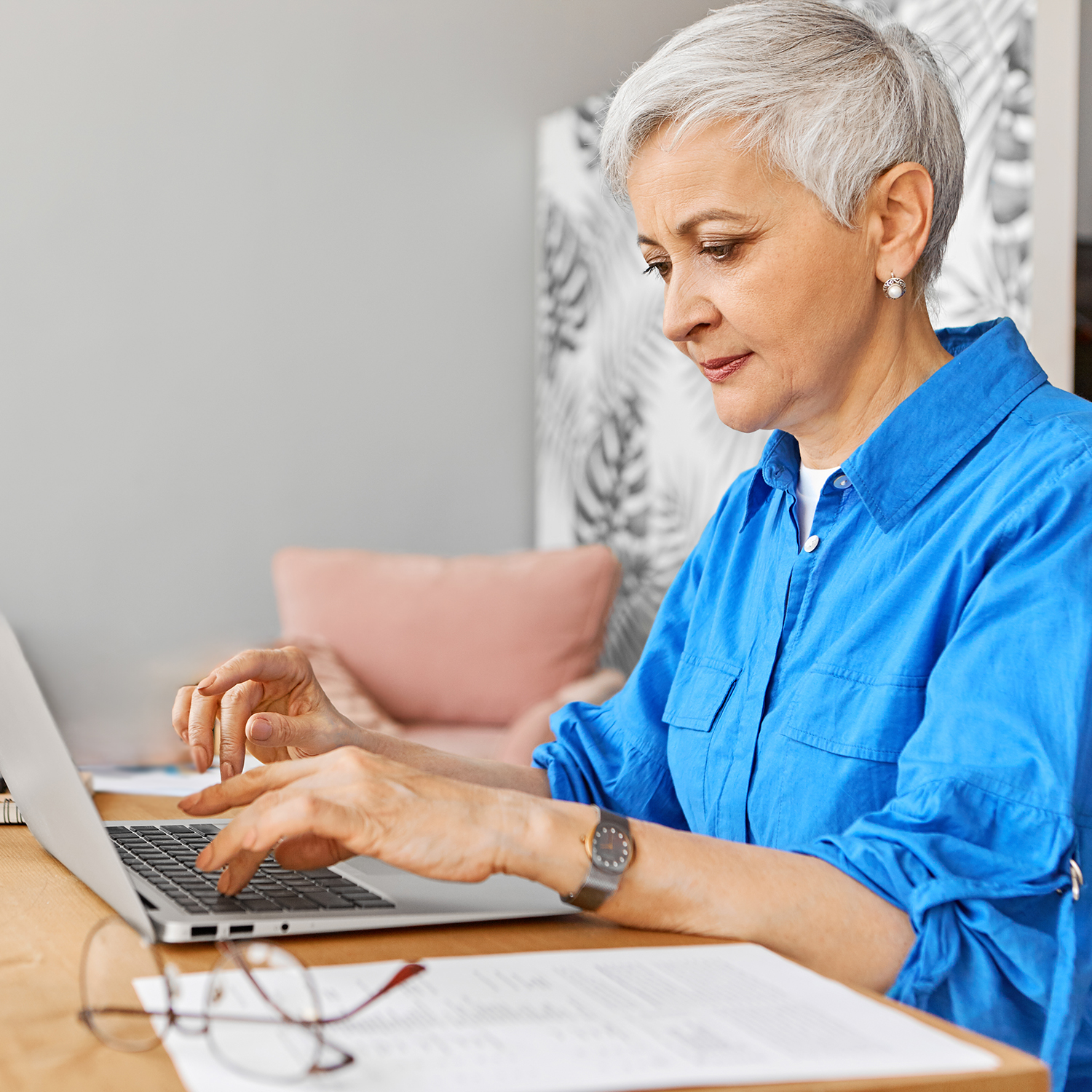 Older woman sitting at a desk working on a laptop
