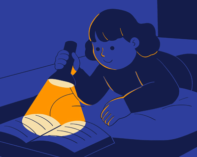 Child reading a book with a flashlight in the dark
